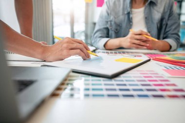 Yaratıcı grafik tasarımcı takımı, iş yerinde yeni bir koleksiyon oluşturmak için renk örnekleri çizelgesi üzerinde çalışıyor..