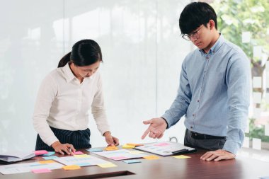 İşletme yürütme ekibi beyin fırtınası yapıyor ve ofiste birlikte pazarlama planlaması için yeni bir iş projesiyle ilgili notlar alıyor..