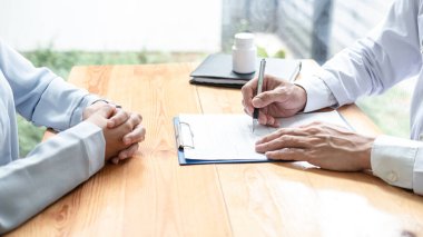 Steteskoplu erkek doktor, hasta geçmişi ve hastalık teşhisi hakkında soru sorarken, klinikteki panoya hasta semptomu, ilaç geçmişi ve reçete yazıyor.