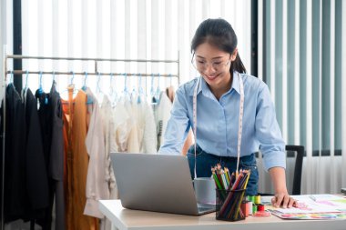 Çalışan ve düşünen kadın moda tasarımcısı atölyede yeni kıyafet koleksiyonu ürünü yapmak için renk örnekleri ve kumaş seçmeye karar verdi.
