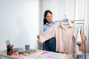 Çalışan ve düşünen kadın moda tasarımcısı atölyede yeni kıyafet koleksiyonu ürünü yapmak için renk örnekleri ve kumaş seçmeye karar verdi.