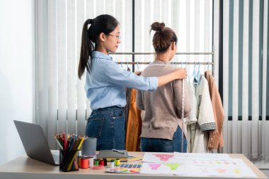 Kadın moda tasarımcısı çalışıyor ve kumaş malzemelerini ölçüyor. Yeni kıyafet koleksiyonu ürünleri yapmak için renk örnekleri seçiyor..