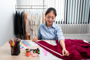 Kadın moda tasarımcısı çalışıyor ve kumaş malzemelerini ölçüyor. Yeni kıyafet koleksiyonu ürünleri yapmak için renk örnekleri seçiyor..