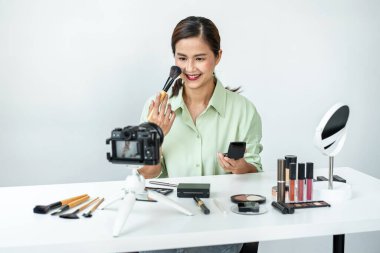 Kadın blogcu, makyaj malzemesi kozmetik inceleme ürünü ve canlı yayın videosunu ofis stüdyosundaki kamera ekranında öğretmenliğe sunuyor..