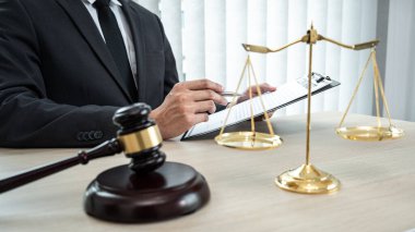 Sözleşme kağıtları, kitap ve ahşap tokmakla çalışan bir erkek avukat veya noter mahkeme salonunda, hukuk ve hukuk hizmetleri kavramında masaya oturur..