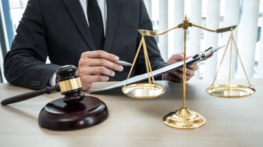 Sözleşme kağıtları, kitap ve ahşap tokmakla çalışan bir erkek avukat veya noter mahkeme salonunda, hukuk ve hukuk hizmetleri kavramında masaya oturur..