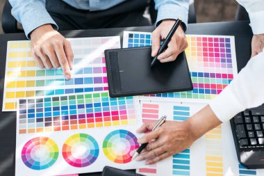 Yaratıcı grafik tasarımcı takımı, iş yerinde yeni bir koleksiyon oluşturmak için renk örnekleri çizelgesi üzerinde çalışıyor.