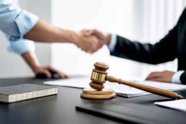 İyi bir iş birliğinden sonra el sıkışan iki kişi, bir yargıcın tokmağının önünde sözleşmeyi tartıştıktan sonra el sıkışıyor..
