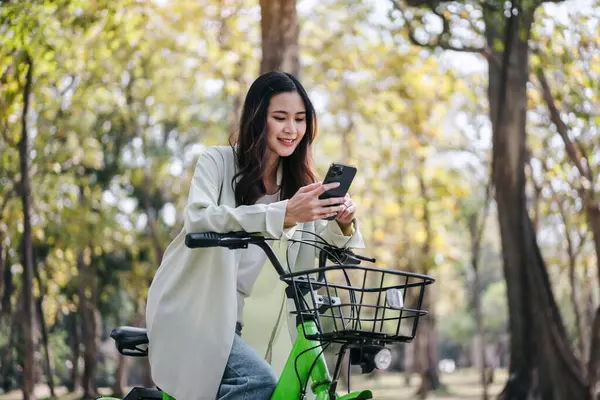 Woman Riding Bike Looking Her Phone She Smiling Seems Enjoying Foto Stock Royalty Free