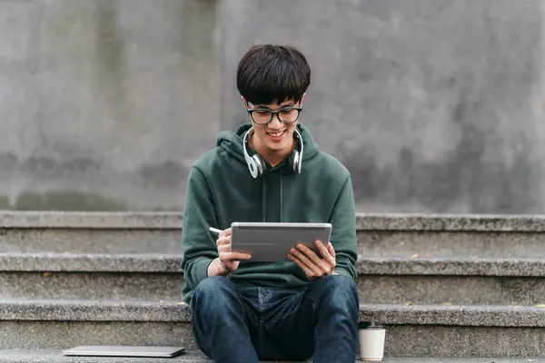 Seorang Pemuda Sedang Duduk Tangga Dengan Sebuah Tablet Tangannya Dia Stok Gambar