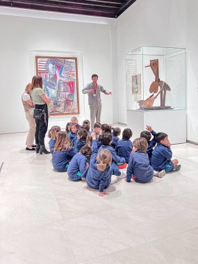 Malaga, İspanya, 6 Mayıs 2024. Malaga 'daki Picasso Müzesi' nde yerde oturan bir grup çocuk. Sanat galerisinde rehberli gezi. 