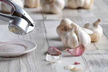 Bir grup taze organik sarımsak soğanı, karanfil ve ahşap zemin üzerinde ezilmiş sarımsak. Seçici odak. 