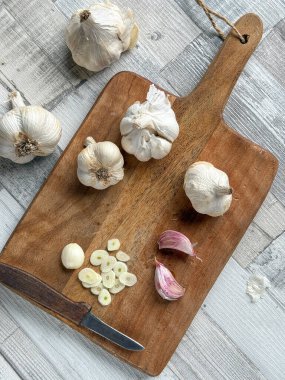 Bir grup taze organik sarımsak soğanı ve tahta kesim tahtasına kesilmiş karanfil.. 