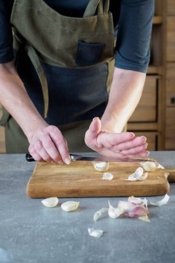 Kadın elleri sarımsağı bıçakla ezme yöntemiyle soyarlar. Genel Görünüm.