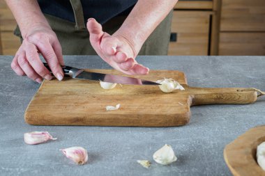 Kadın elleri sarımsağı bıçakla ezme yöntemiyle soyarlar. Genel Görünüm.