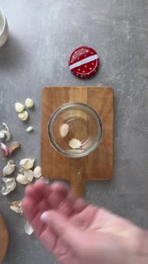 Dişi eller sarımsak soyarken kavanozun titreme metodunu kullanır. Tepeden çekim. 