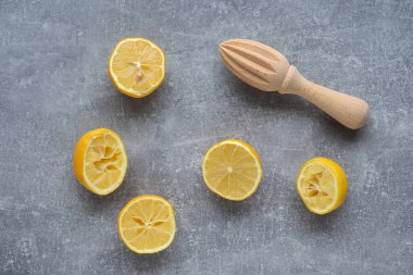Arta kalan limon kabukları ve gri arka planda ahşap squizer. Tepeden çekim.