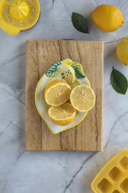 Yarım limon, sarı silikon buz küpü tepsisi ve gri arka planda squizer. Tepeden çekim.