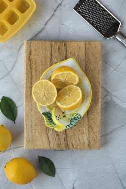 Yarım limon, sarı silikon buz tepsisi ve gri arka planda rende. Tepeden çekim.