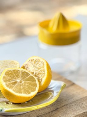 Freshly cut lemon halves on a wooden cutting board with a glass citrus juicer in the background. Bright and vibrant citrus scene. clipart