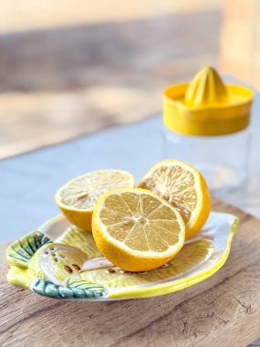 Freshly cut lemon halves on a wooden cutting board with a glass citrus juicer in the background. Bright and vibrant citrus scene. clipart