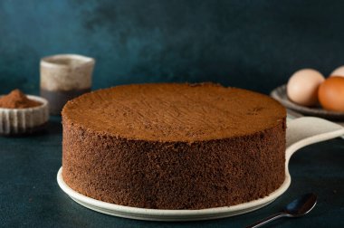 Homemade round chocolate sponge cake or chiffon cake. Sponge cake ingredients: eggs, flour and cocoa. Chocolate biscuit.