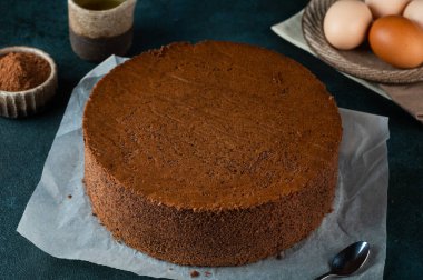 Homemade round chocolate sponge cake or chiffon cake. Sponge cake ingredients: eggs, flour and cocoa. Chocolate biscuit.