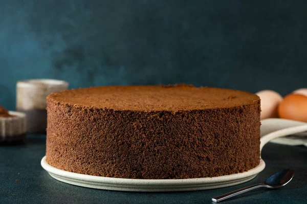 Homemade round chocolate sponge cake or chiffon cake. Sponge cake ingredients: eggs, flour and cocoa. Chocolate biscuit.