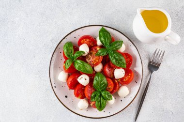 Dilimlenmiş domatesli İtalyan caprese salatası, mozzarella, fesleğen, hafif arka planda zeytinyağı. Üst Manzara. İtalyan yemeği. Sağlıklı salata. Yaz yemeği.