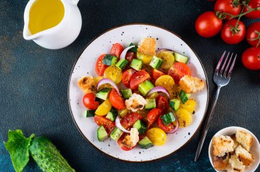 Domatesli, soğanlı ve kızarmış ekmekli vejetaryen salatası. Karanlık arka plan. Üst Manzara. İtalyan salatası.