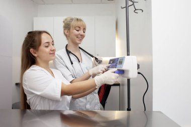 two female nurses in uniform use an infusator in a hospital, doctors connect the equipment against the background of the workplace