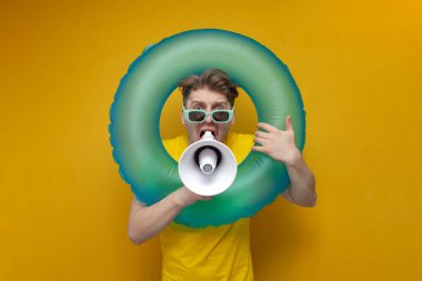 Yazın tatilde olan genç adam bağırır ve sarı arka planda megafonla haber verir. Şişme yüzme çemberi olan bir adam yüksek sesle konuşur.