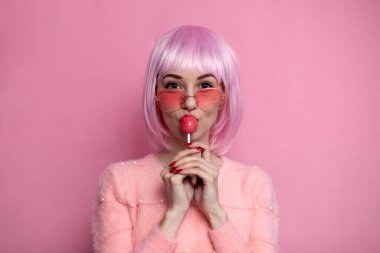 Pembe kısa saçlı genç kız, zevkle yalayarak ve yalayarak, seksi bir konsept.