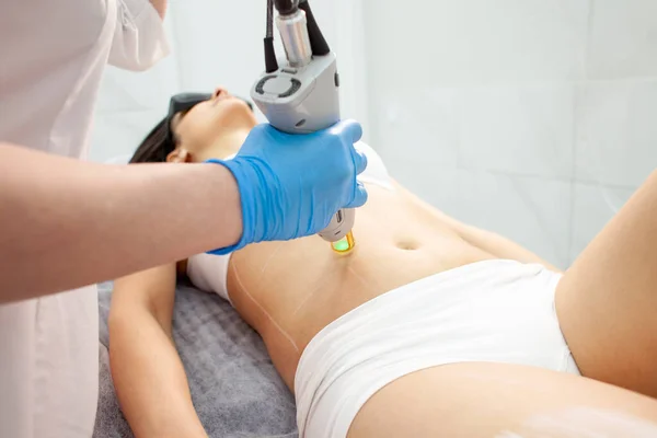 stock image Epilation of the abdomen in a cosmetology clinic. Doctor cosmetologist makes a procedure for removing hair on the abdomen with an alexandrite laser, close-up