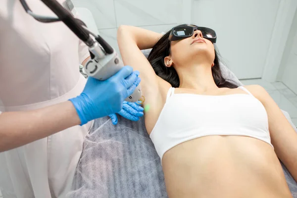 armpit epilation in a cosmetology clinic. female patient doing armpit hair removal procedure with alexandrite laser, epilation with modern equipment