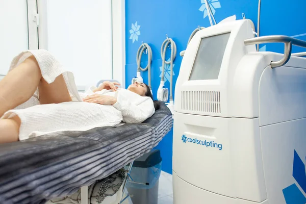 female patient lies on a couch in a cosmetology clinic for a fat removal procedure, coolscalping procedure in a cosmetology clinic
