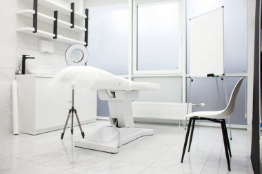 Boş beyaz güzellik salonu. Modern kozmetoloji ekipmanlarıyla tıbbi bir oda ve klinikte bir kanepe, yeni bir kozmetoloji odasının içinde insanlar olmadan.