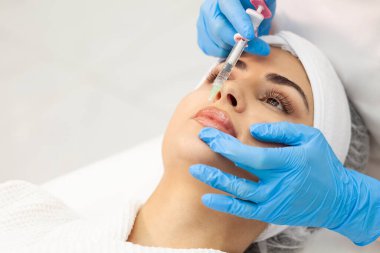 lip augmentation procedure using botox in cosmetology clinic, cosmetologist doctor in gloves makes injection with syringe in the patient's lips, close-up of syringe and needle