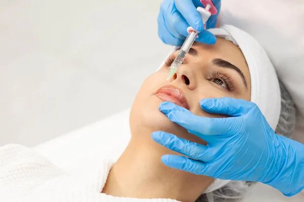 lip augmentation procedure using botox in cosmetology clinic, cosmetologist doctor in gloves makes injection with syringe in the patient\'s lips, close-up of syringe and needle