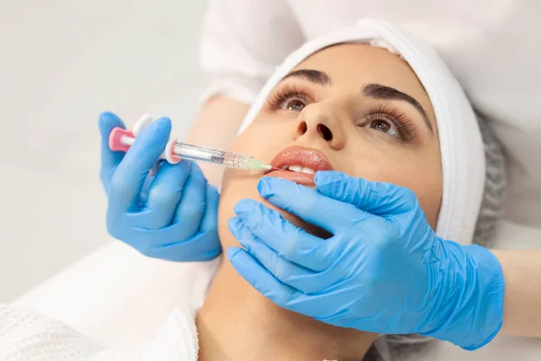 lip augmentation procedure using botox in cosmetology clinic, cosmetologist doctor in gloves makes injection with syringe in the patient\'s lips, close-up of syringe and needle
