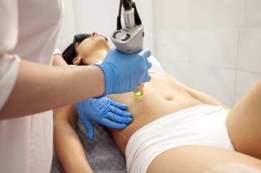 procedure of epilation of the abdomen in cosmetology clinic, cosmetologist makes depilation with alexandrite laser, the process of hair removal with modern equipment