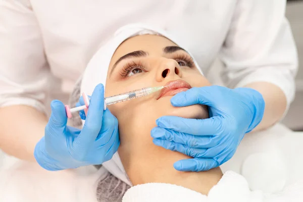 lip augmentation procedure using botox in cosmetology clinic, cosmetologist doctor in gloves makes injection with syringe in the patient's lips, close-up of syringe and needle