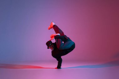 young guy dancer break dancing in neon red blue lighting, active energetic man doing acrobatic tricks, crazy moves and dancer poses