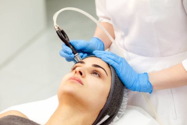 procedure of vacuum cleaning of the face, doctor cosmetologist makes vacuum cleaning of the face of girl to patient in cosmetology clinic, close-up