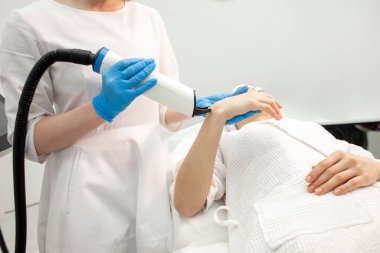 doctor cosmetologist makes laser cleaning of the skin on the arm of the patient with modern professional equipment, woman client lies at session in cosmetology clinic, fractional laser resurfacing