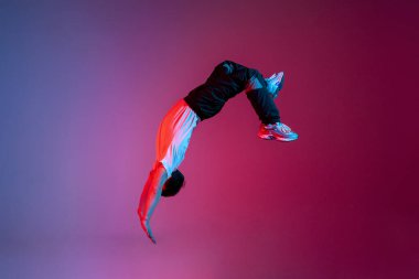 young guy falls upside down in the air, man levitates and flies down in neon lighting, acrobat dancer flies in a jump, concept of dreams and fantasies