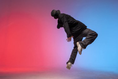 young guy falls upside down in the air, man levitates and flies down in neon lighting, acrobat dancer flies in a jump, concept of dreams and fantasies