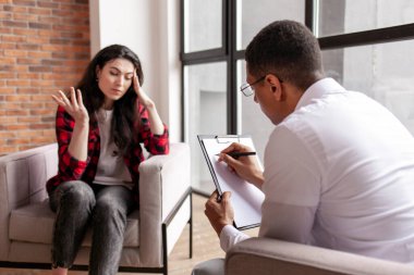 Psikologla seans, kadın hasta psikolog ofisinde oturur ve sorunlarını anlatır. Afrika kökenli Amerikalı erkek psikoterapist hastayı dinler ve teşhisi yazar.