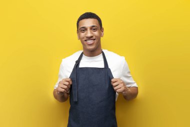 Sarı arka plandaki Afro-Amerikalı garson fotokopi odasına, teslimat servisine, önlüklü garsona bakıyor.