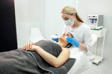 procedure of ultrasonic cavitation facial peeling. facial skin care in cosmetology clinic, woman beautician makes facial cleaning to client